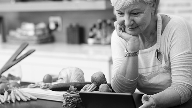 woman looking at tablet while cooking