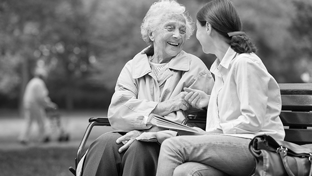 senior woman and daughter sitting on bench