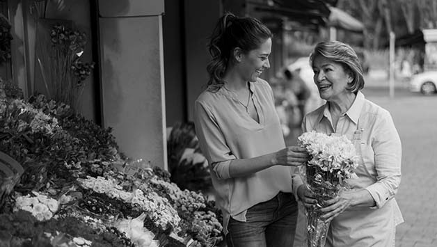 adult daughter with senior mother buying flowers