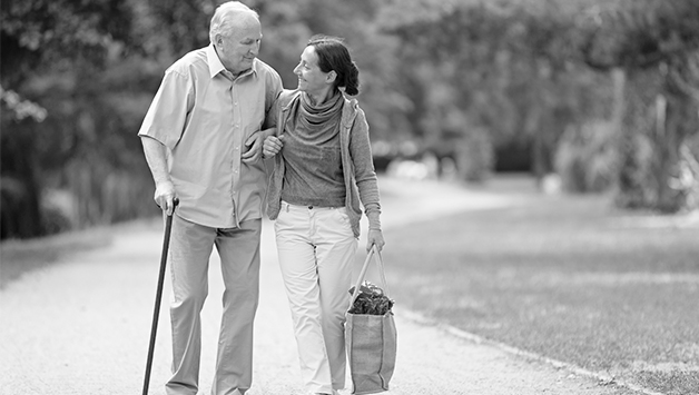 man with cane and woman walking on sidewalk