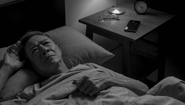senior man lying awake with insomnia