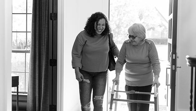 daughter helps mother enter door with walker