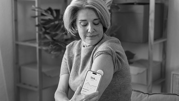 woman checking diabetes patch with phone
