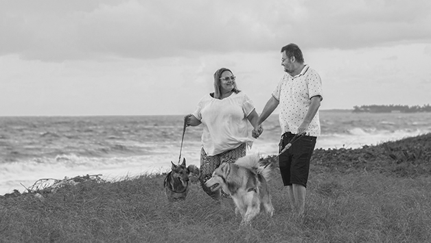 woman and man walking dogs on the beach
