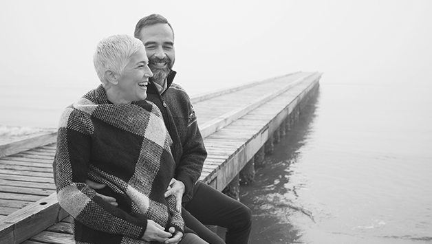 senior man and woman sitting on lake dock