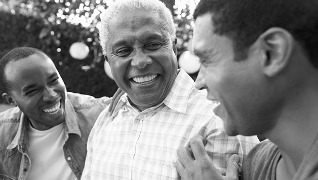 senior man laughing with two adult sons