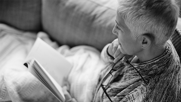 woman reading book on couch